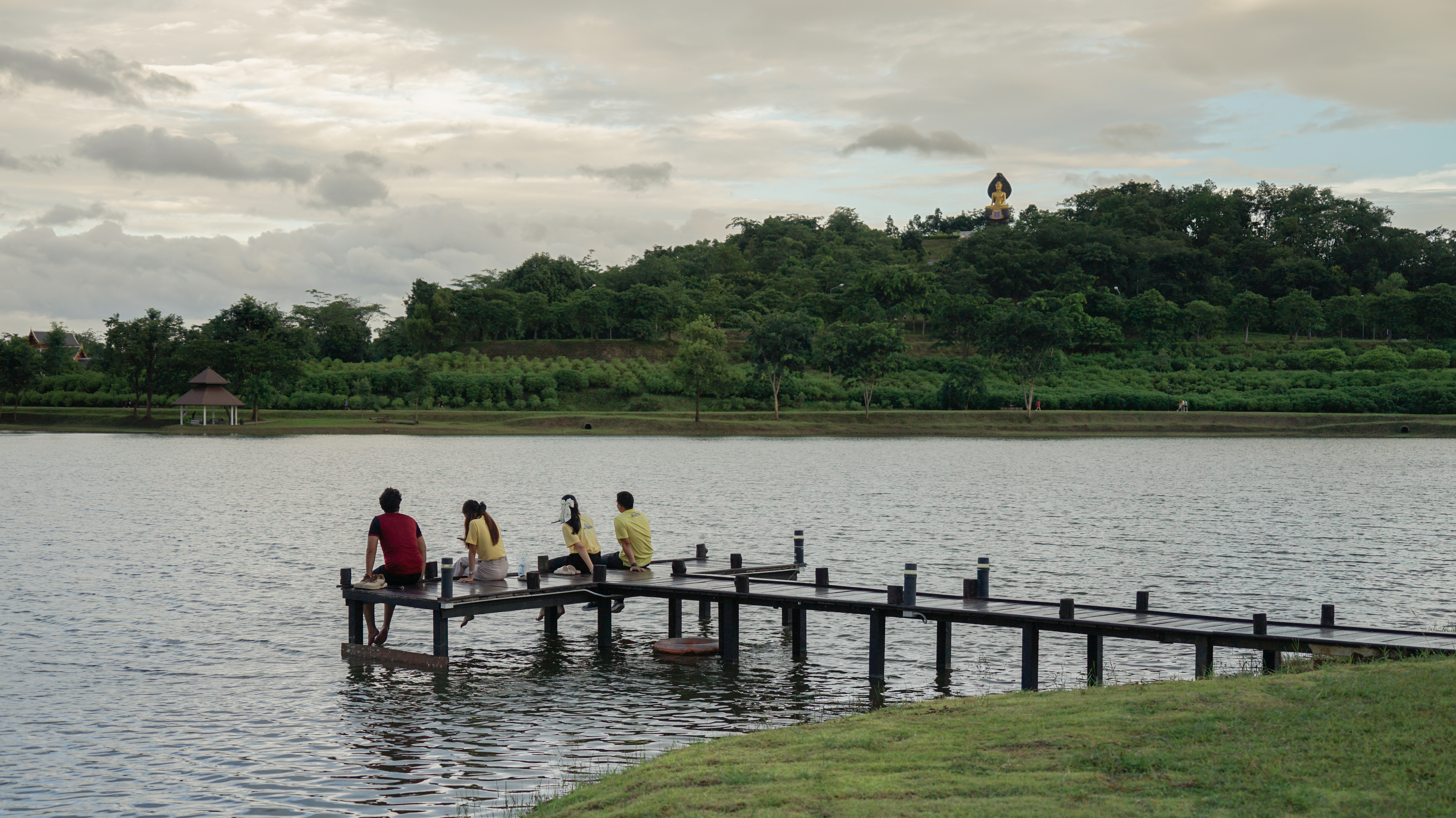 People sitting on a wooden dock over the campus lake